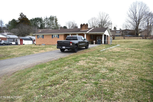 view of front of house featuring aphalt driveway, a chimney, fence, and brick siding