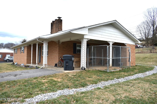 view of side of home with brick siding, driveway, a chimney, and a lawn