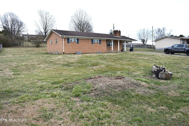 view of front of house with a front yard, brick siding, fence, and a chimney