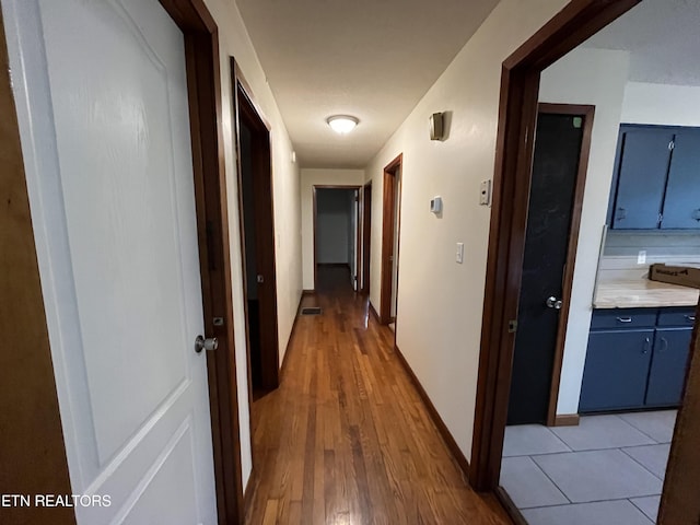 hall with light wood-style floors and baseboards