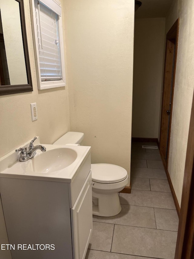 bathroom featuring visible vents, toilet, vanity, tile patterned flooring, and baseboards