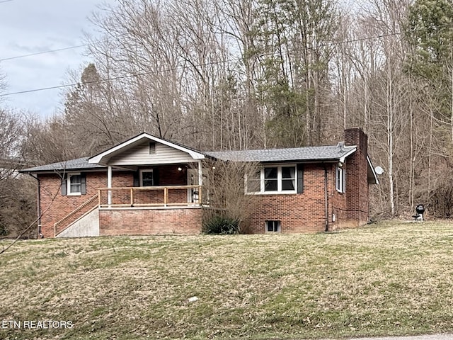 ranch-style home featuring brick siding, covered porch, a chimney, and a front yard