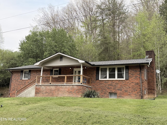 single story home featuring a chimney, brick siding, a porch, and a front lawn