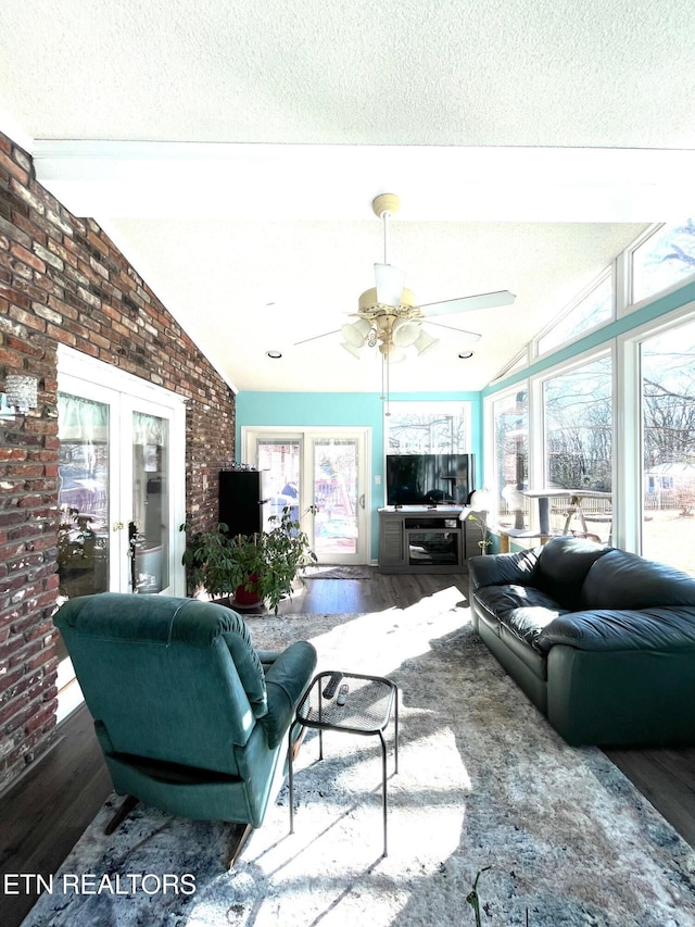 living area featuring a textured ceiling, a ceiling fan, lofted ceiling, and wood finished floors