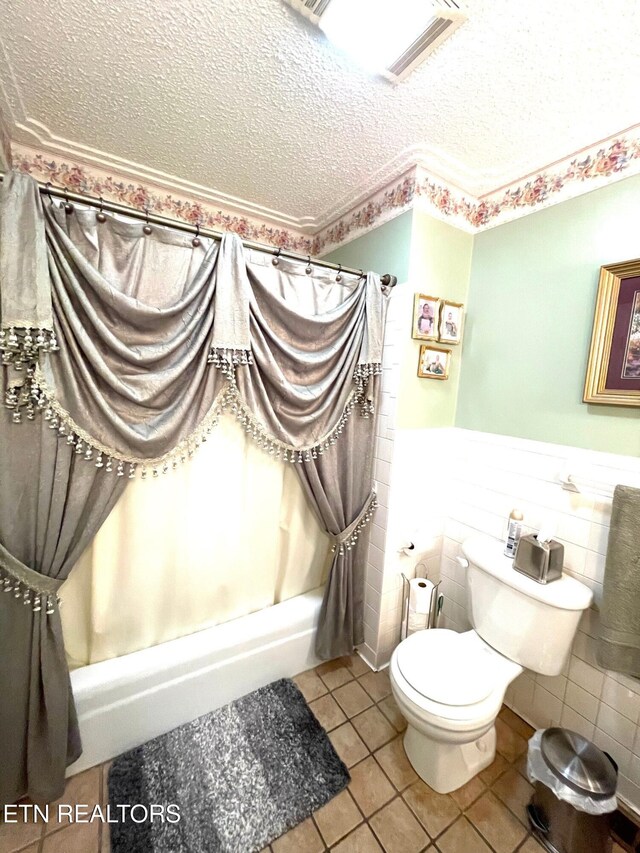 full bath with tile patterned flooring, visible vents, a wainscoted wall, toilet, and a textured ceiling