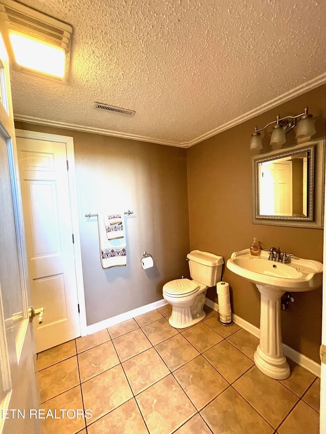 bathroom featuring tile patterned floors, visible vents, toilet, a textured ceiling, and baseboards