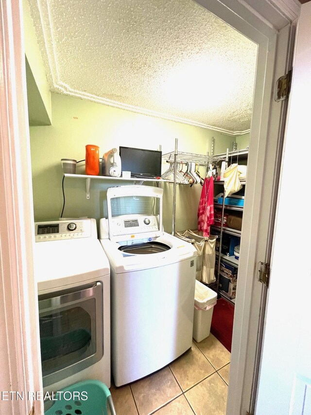 laundry area featuring a textured ceiling, laundry area, light tile patterned floors, and washing machine and clothes dryer