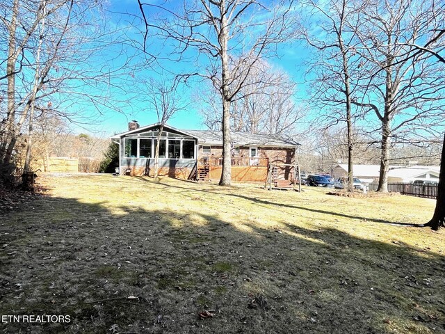 exterior space with fence, a sunroom, and a chimney