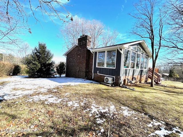 snow covered property featuring ac unit, a chimney, and a sunroom