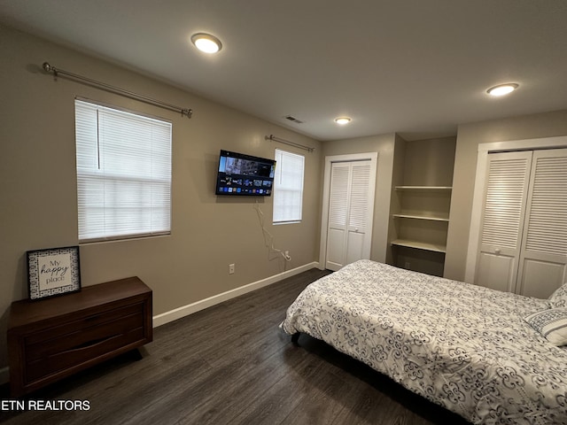 bedroom featuring dark wood-type flooring, multiple closets, visible vents, and baseboards