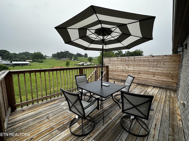 wooden deck with a yard, a rural view, and outdoor dining space