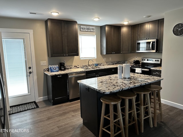 kitchen with visible vents, dark wood-style floors, stainless steel appliances, a kitchen bar, and a sink