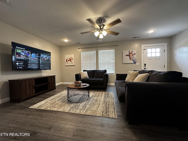 living area featuring dark wood-style floors, visible vents, a ceiling fan, and baseboards