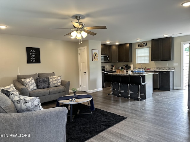 living area with wood finished floors, a ceiling fan, and baseboards