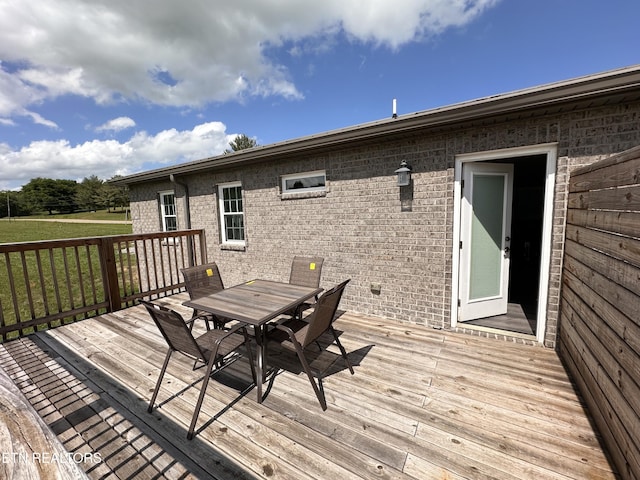 wooden deck featuring outdoor dining area and a lawn