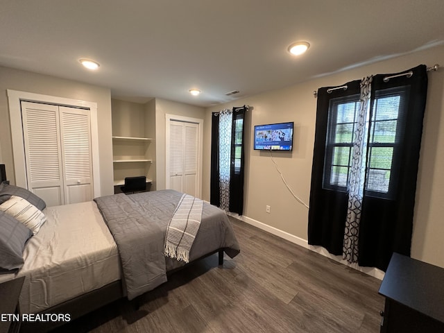 bedroom featuring dark wood-style floors, two closets, visible vents, and baseboards