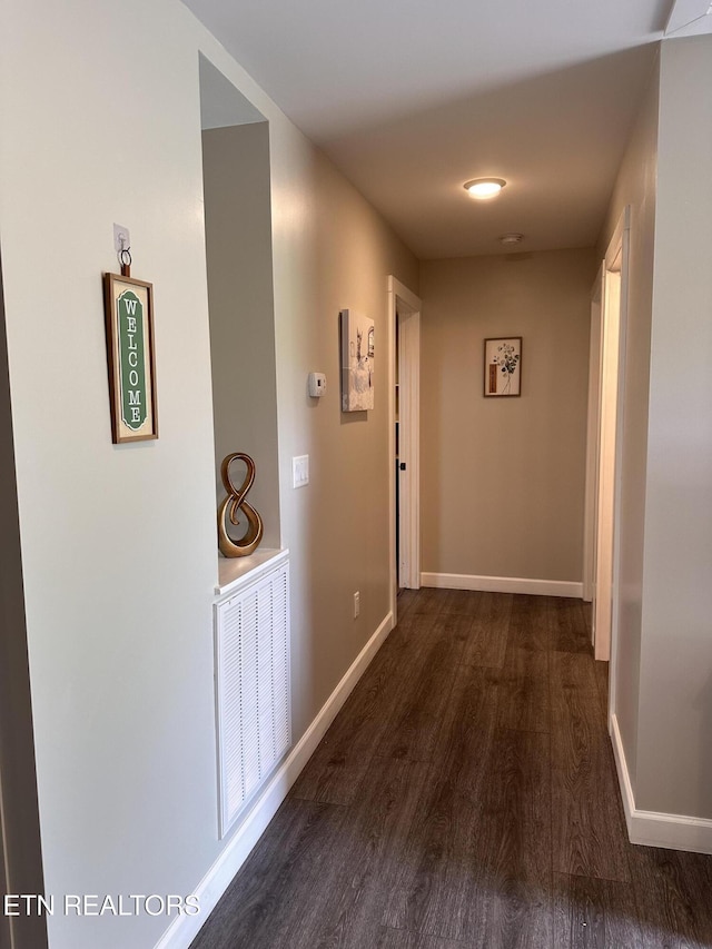 hall featuring visible vents, dark wood finished floors, and baseboards