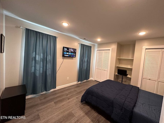 bedroom featuring two closets, baseboards, wood finished floors, and recessed lighting