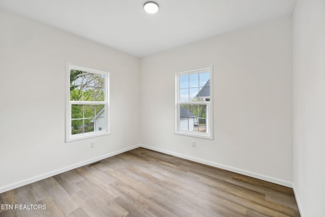 empty room with visible vents, baseboards, and wood finished floors
