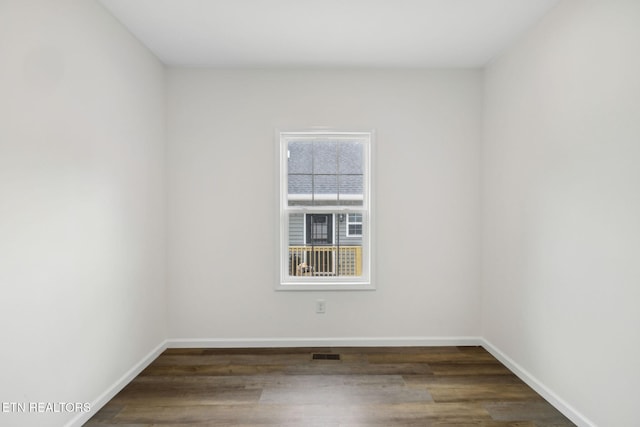 unfurnished room featuring visible vents, baseboards, and wood finished floors