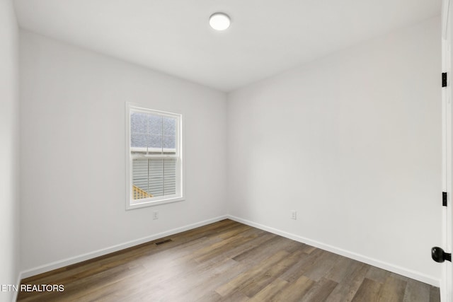 unfurnished room featuring visible vents, baseboards, and wood finished floors