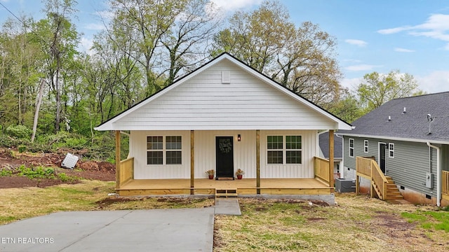 bungalow-style home featuring central air condition unit, board and batten siding, and covered porch