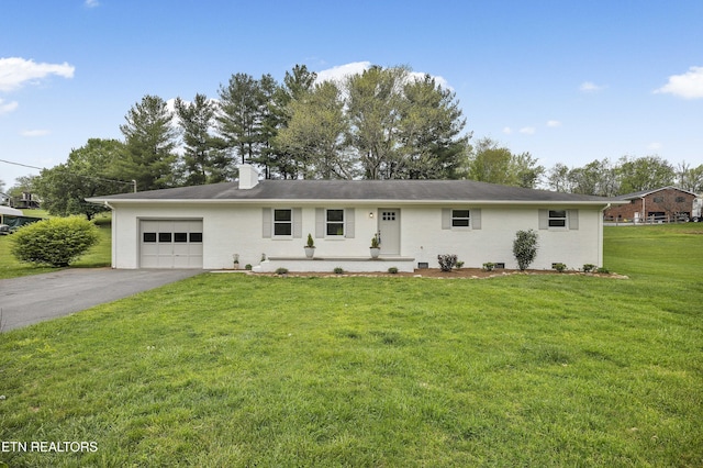 ranch-style home with aphalt driveway, a chimney, an attached garage, and a front yard