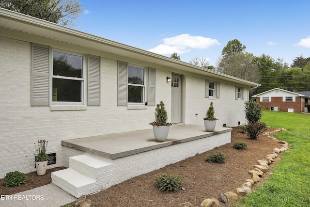 view of front of property with brick siding, crawl space, and a front lawn