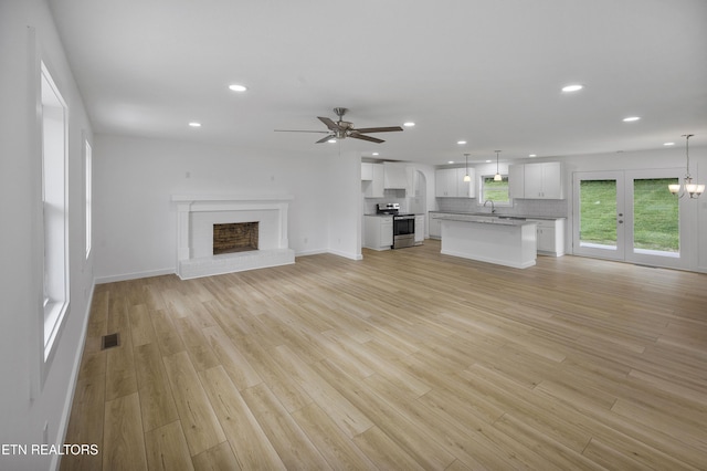 unfurnished living room with light wood-style floors, recessed lighting, a fireplace, and a sink