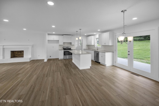 kitchen featuring stainless steel appliances, wood finished floors, visible vents, and decorative backsplash