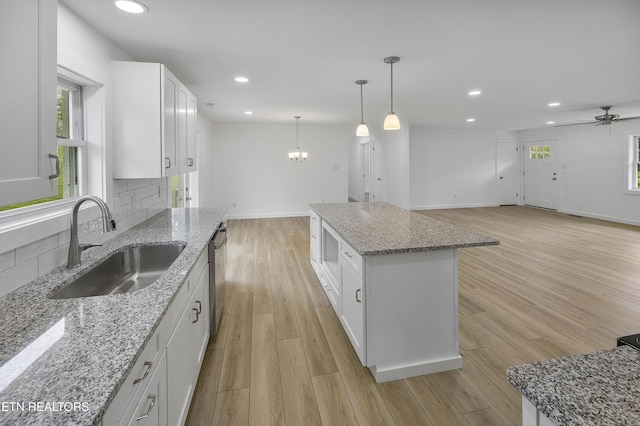 kitchen featuring light wood-style flooring, a sink, white cabinetry, a center island, and tasteful backsplash