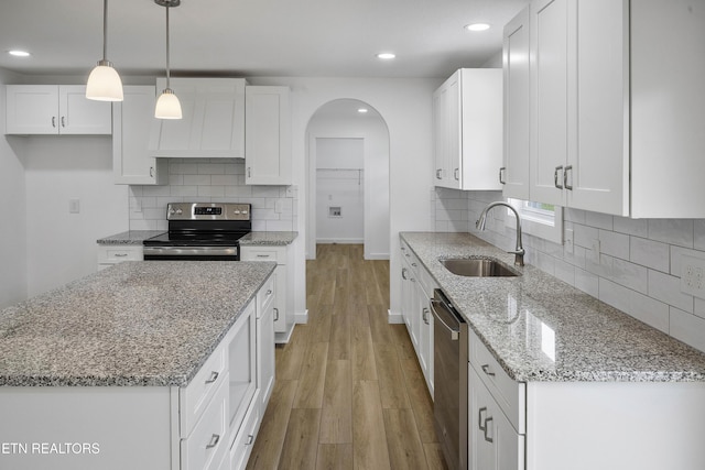 kitchen with stainless steel appliances, a sink, white cabinetry, custom exhaust hood, and light wood finished floors