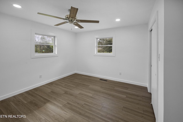 unfurnished bedroom with multiple windows, visible vents, dark wood finished floors, and recessed lighting