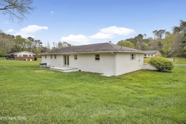 back of house featuring a lawn and brick siding