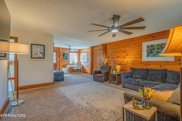 carpeted living room with ceiling fan, wooden walls, and baseboards