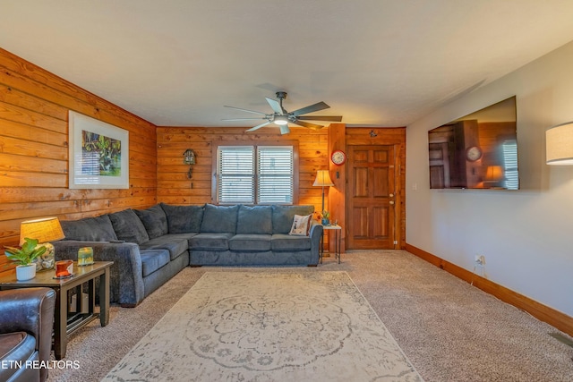 living room featuring baseboards, wood walls, a ceiling fan, and light colored carpet