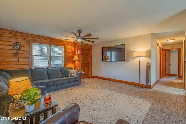 carpeted living room featuring a ceiling fan, wooden walls, and baseboards