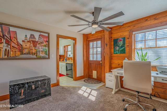 office space featuring a ceiling fan, light carpet, a sink, light tile patterned flooring, and baseboards