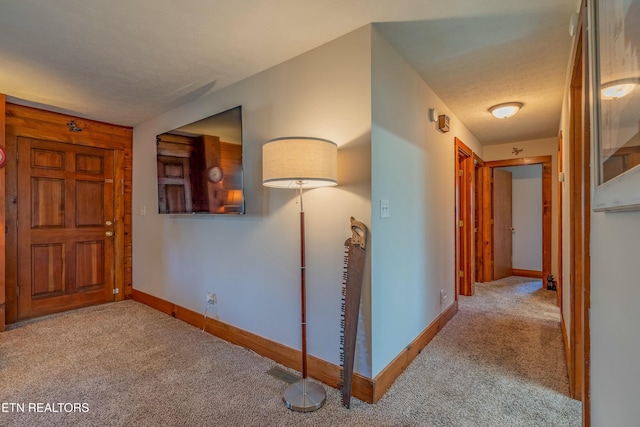 hall with visible vents, carpet flooring, a textured ceiling, and baseboards