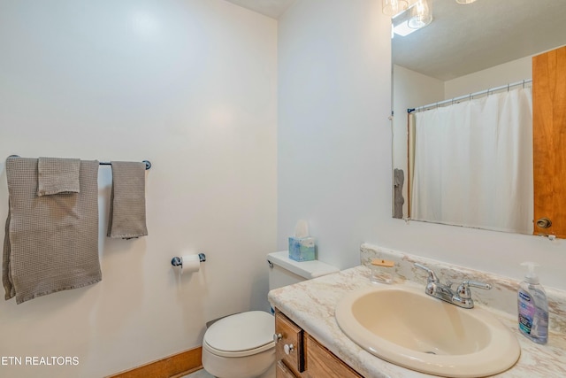 bathroom featuring toilet, vanity, and a shower with curtain