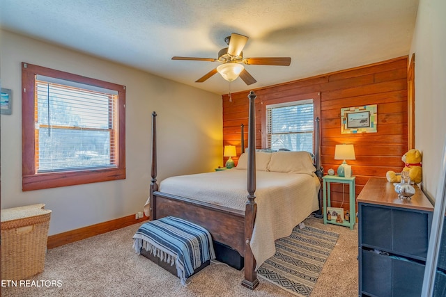 bedroom featuring carpet floors, ceiling fan, wooden walls, a textured ceiling, and baseboards