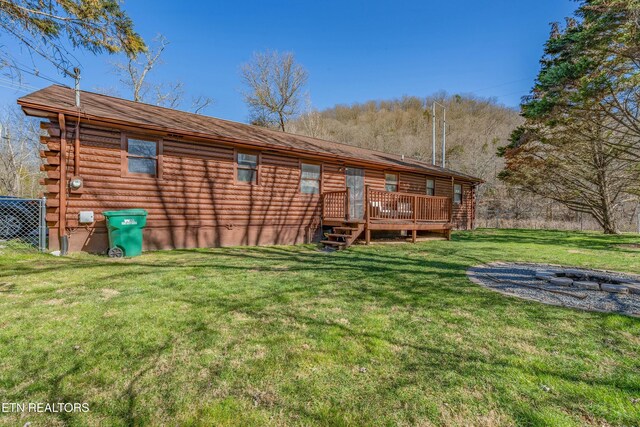 rear view of property featuring a deck, log exterior, and a lawn