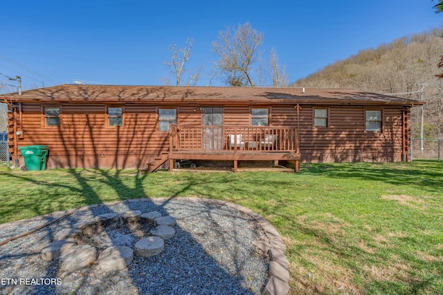 rear view of house with a deck, log exterior, a yard, and an outdoor fire pit