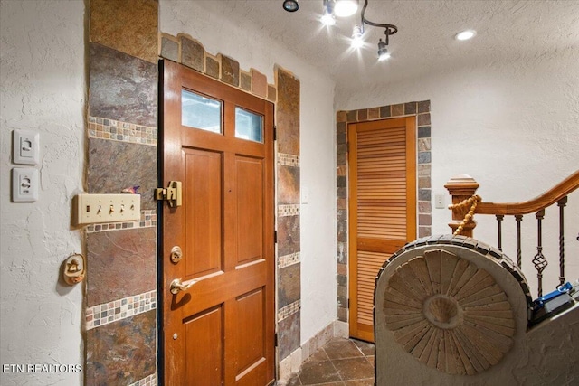 entryway with stairway, a textured wall, and a textured ceiling