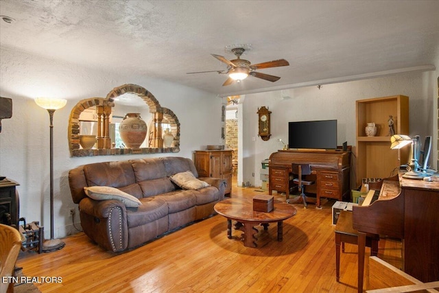 living room featuring ceiling fan, a textured ceiling, wood finished floors, and a textured wall