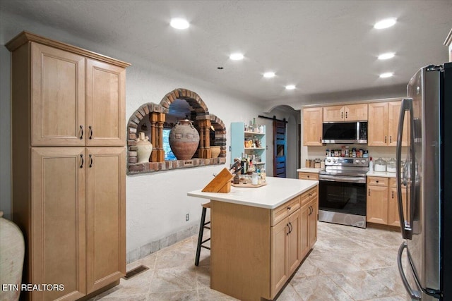 kitchen featuring a center island, light countertops, a barn door, appliances with stainless steel finishes, and light brown cabinets