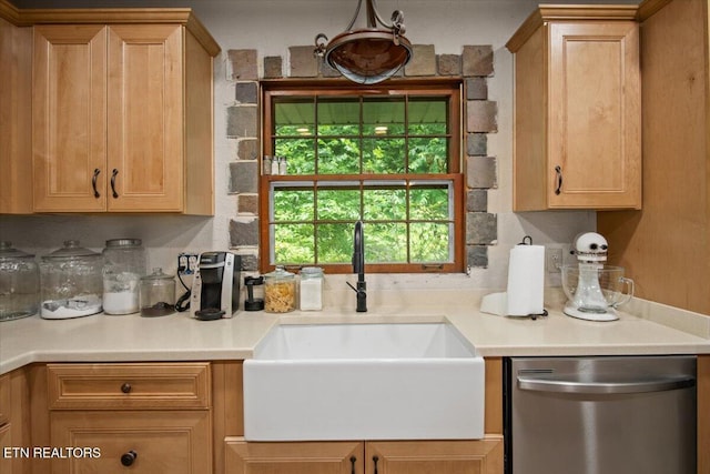 kitchen featuring light brown cabinets, light countertops, stainless steel dishwasher, and a sink