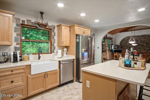 kitchen with arched walkways, light brown cabinets, a sink, light countertops, and appliances with stainless steel finishes