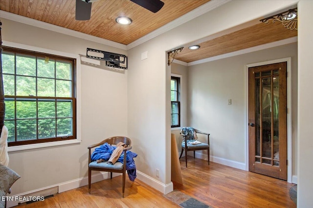 sitting room with light wood finished floors, a healthy amount of sunlight, wood ceiling, and crown molding