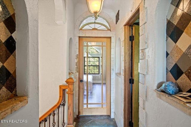 doorway featuring stone tile floors, arched walkways, and a textured wall